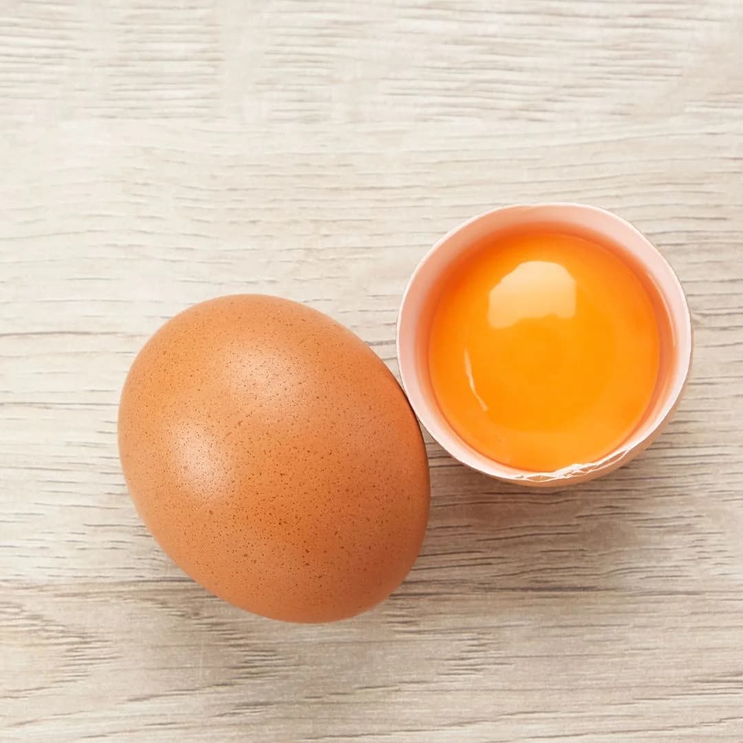 Raw egg with broken shell showing egg yolk inside