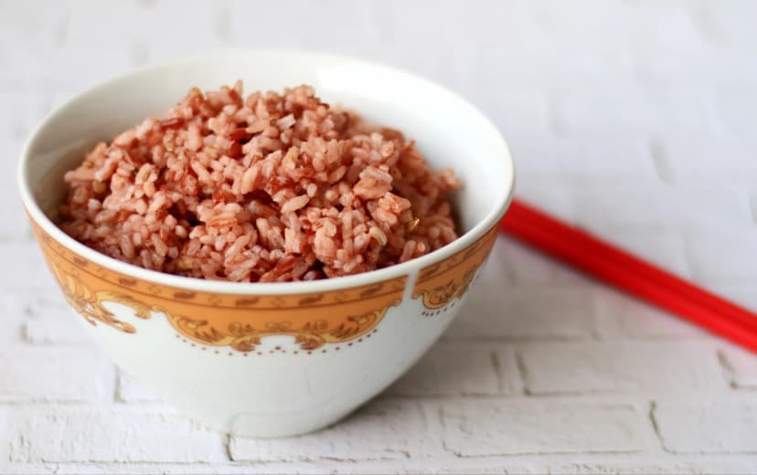front view coocked red rice served in white bowl