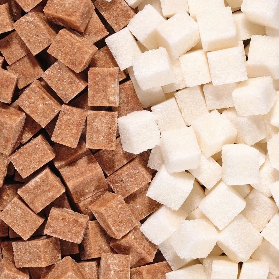 Cubes of refined white sugar and brown sugar placed side by side on a table