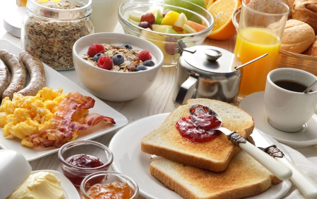 Healthy breakfast with scrambled eggs, toast, jam, fruit salad, cereal, and coffee