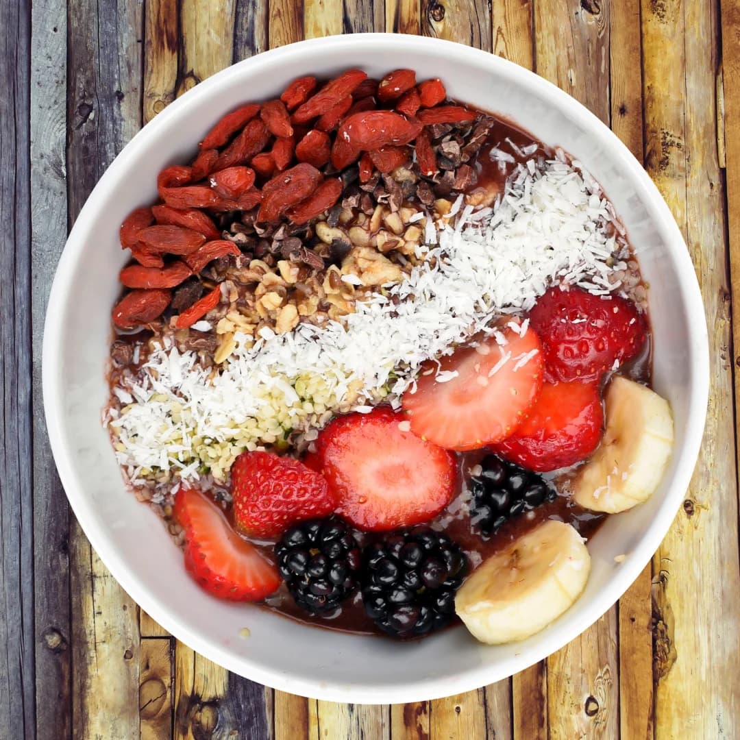 Healthy acai bowl topped with strawberries, banana, blackberries, goji berries, coconut flakes, nuts, and seeds