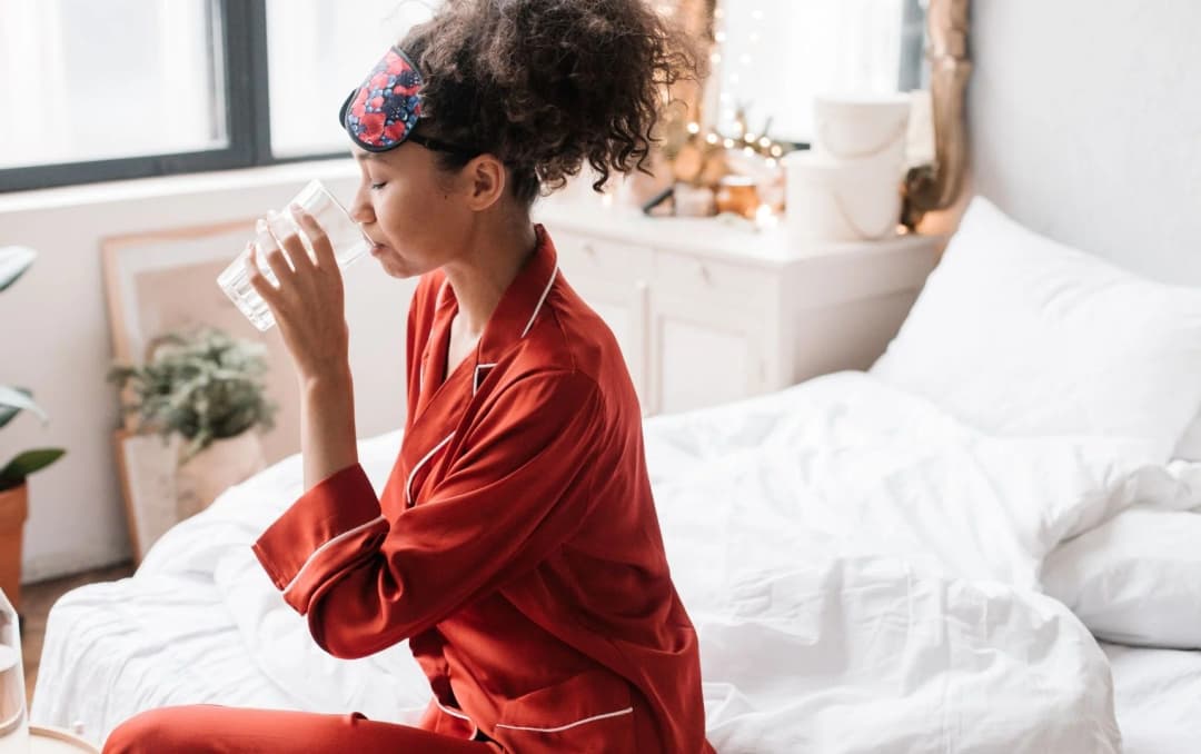 side view of a girl drinking water in bed after wakeup