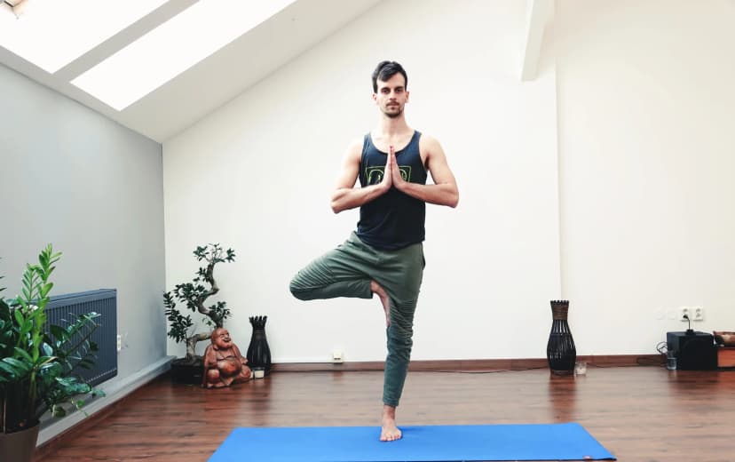 a men doing tre pose of yoga in the yoga mat morning view in the house