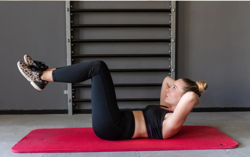 woman performing abdominal crunches on a red exercise mat.