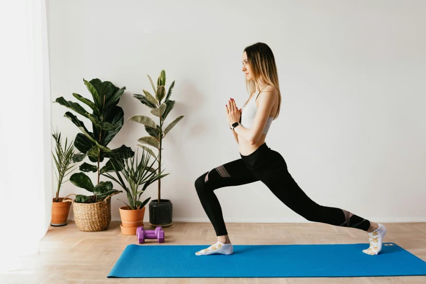 Woman performing lunges on yoga mat at home