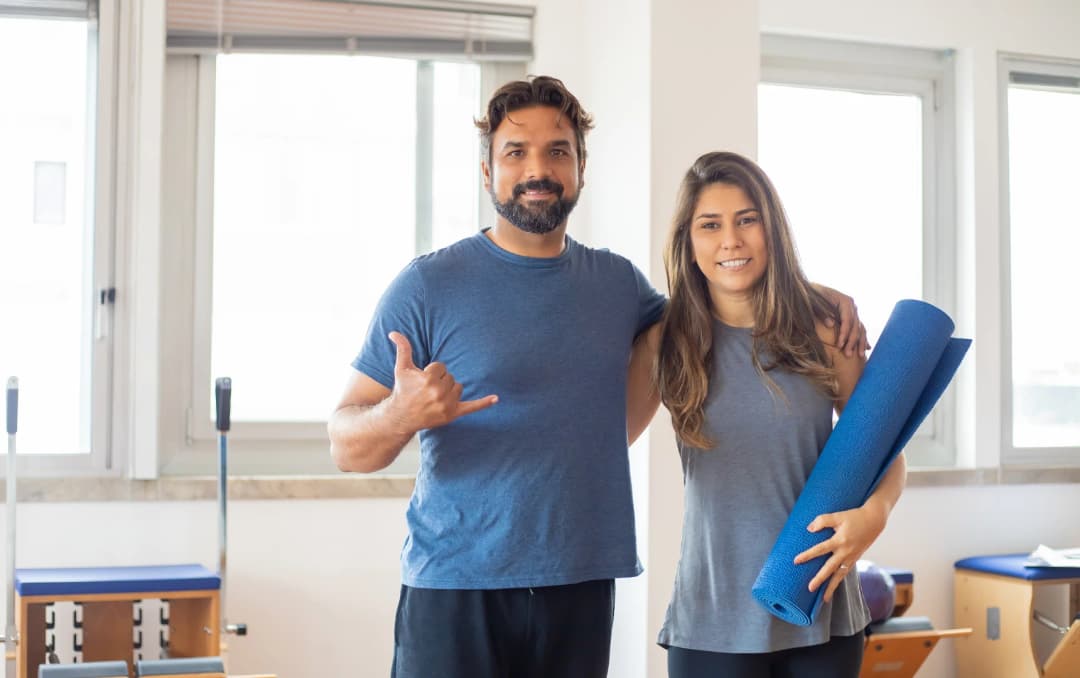 Man and woman holding a yoga mat after a home workout session